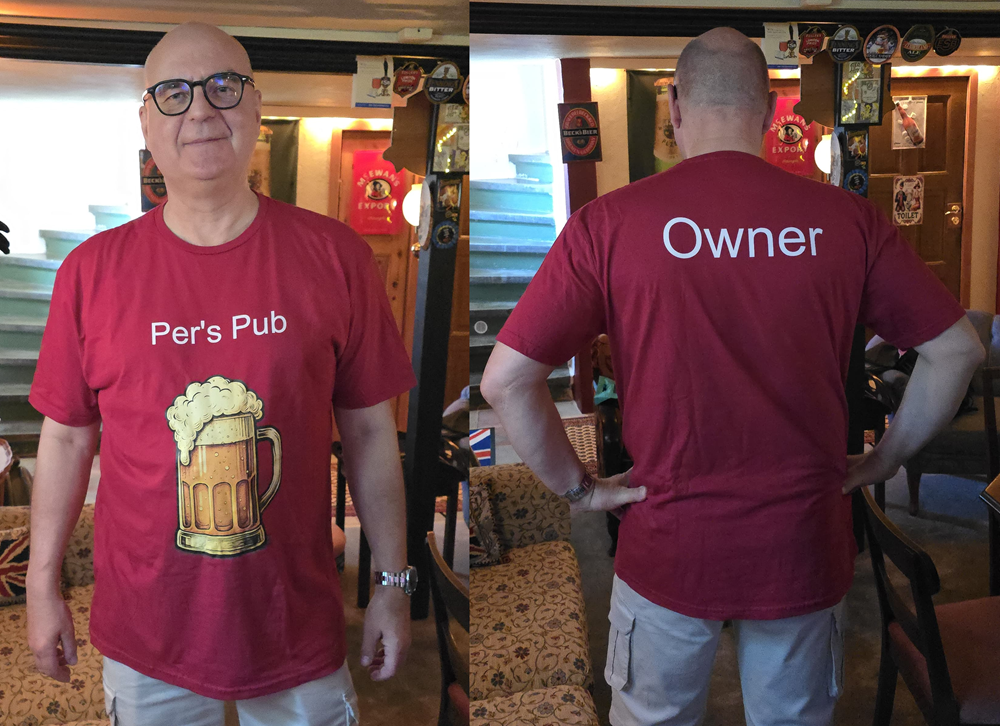 Per visar upp sin nya tröja. Text på framsidan är Per's Pub och på baksidan Owner.