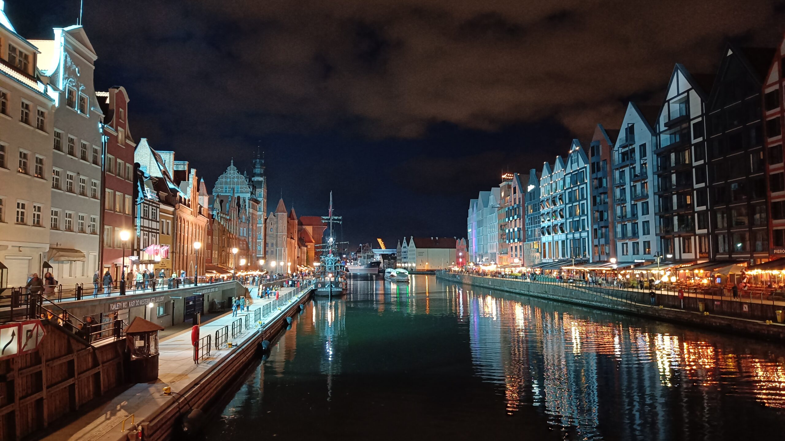 Gdansk by night i början av oktober. Staden sett i kvällsbelysning från en bro, med vatten och hus.